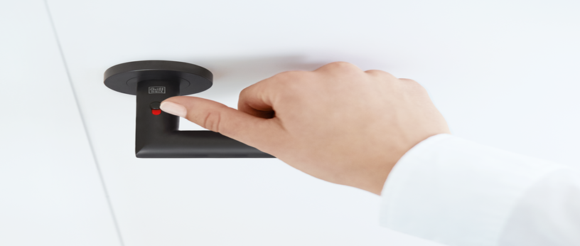 Hand bedient den roten Fingerprint-Sensor des schwarzen Türgriffs me time mit Smart2Lock-Technologie an einer weißen Tür.