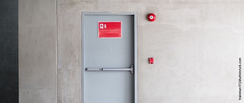 Robuste Brandschutztür mit Warnhinweis und Feueralarm an einer Kellerwand